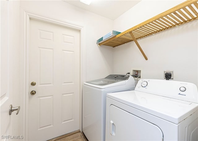 laundry area with independent washer and dryer and light tile patterned floors