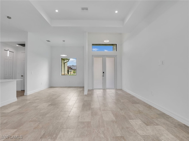 foyer featuring a raised ceiling, light hardwood / wood-style flooring, and french doors