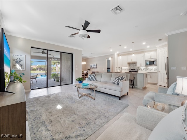 tiled living room with ornamental molding and ceiling fan