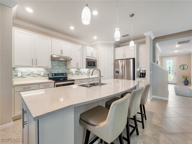 kitchen featuring white cabinets, an island with sink, sink, decorative light fixtures, and stainless steel appliances