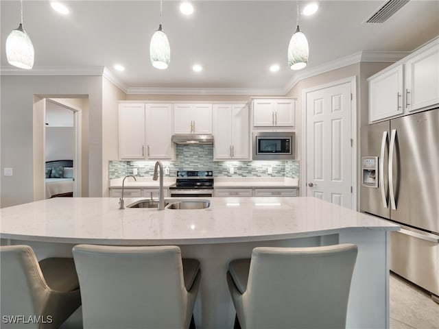 kitchen featuring pendant lighting, white cabinets, an island with sink, and appliances with stainless steel finishes