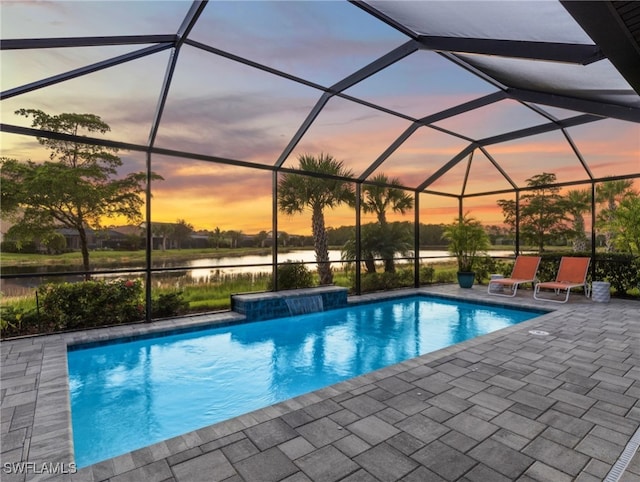 pool at dusk with a lanai, a patio area, a water view, and pool water feature