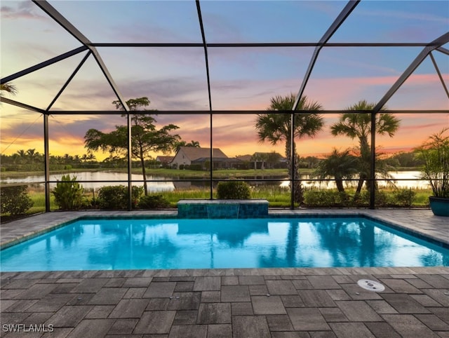 pool at dusk featuring a patio, a water view, and a lanai