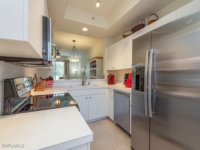 kitchen featuring white cabinets, a raised ceiling, hanging light fixtures, sink, and appliances with stainless steel finishes