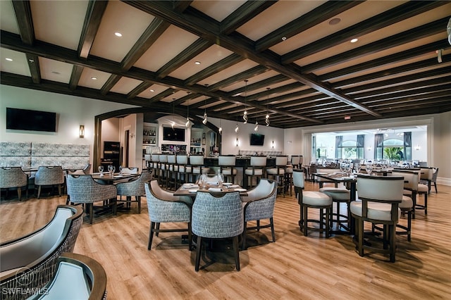 dining room with bar, coffered ceiling, light hardwood / wood-style flooring, and beamed ceiling