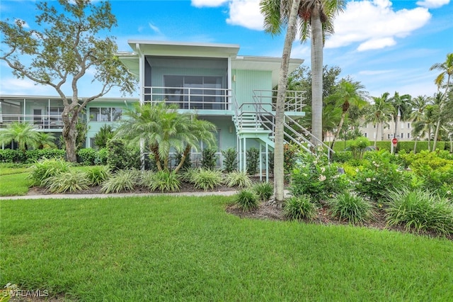 rear view of house featuring a yard and a sunroom