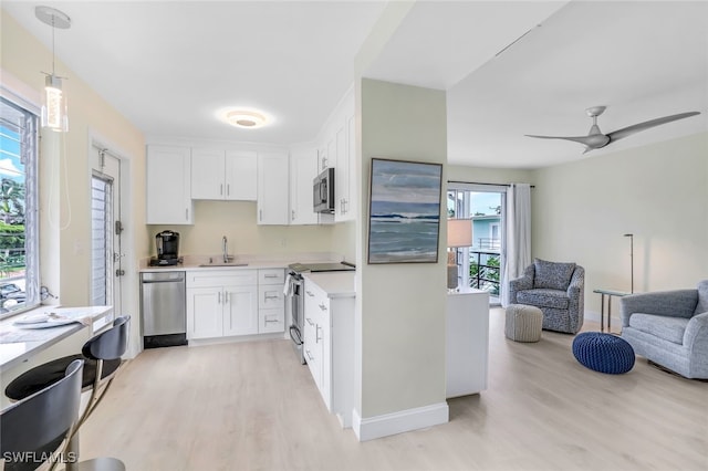 kitchen featuring ceiling fan, white cabinets, decorative light fixtures, appliances with stainless steel finishes, and light hardwood / wood-style floors