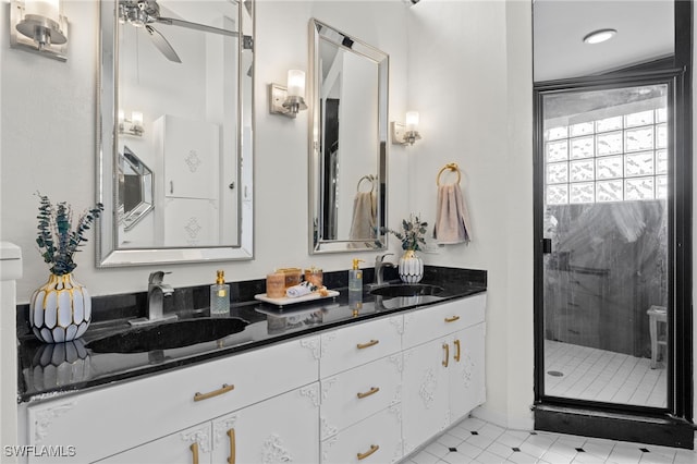 bathroom with a stall shower, double vanity, ceiling fan, and baseboards