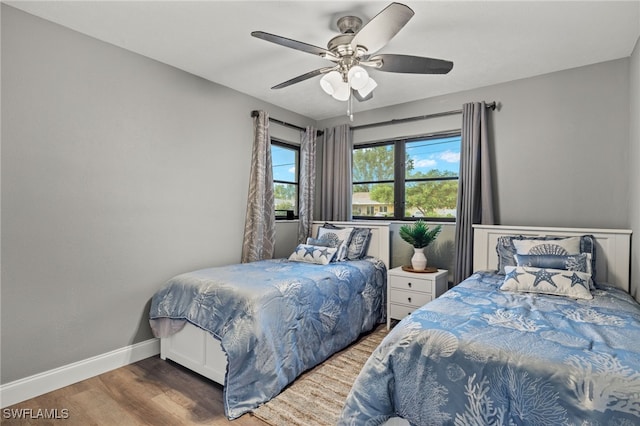 bedroom with wood finished floors, baseboards, and a ceiling fan