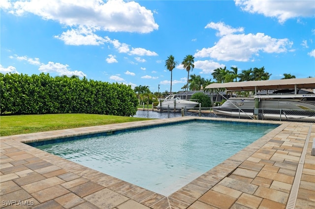 swimming pool with a boat dock, a yard, boat lift, and a patio area