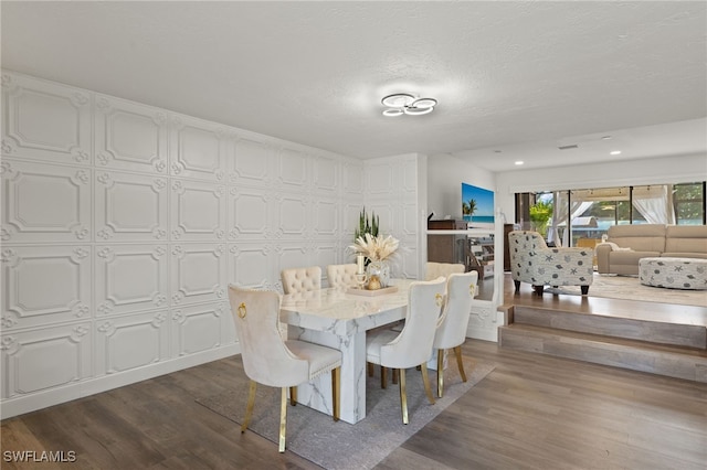 dining space featuring wood finished floors, a textured ceiling, and recessed lighting