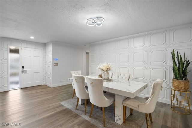 dining area featuring wood finished floors, a textured ceiling, and recessed lighting