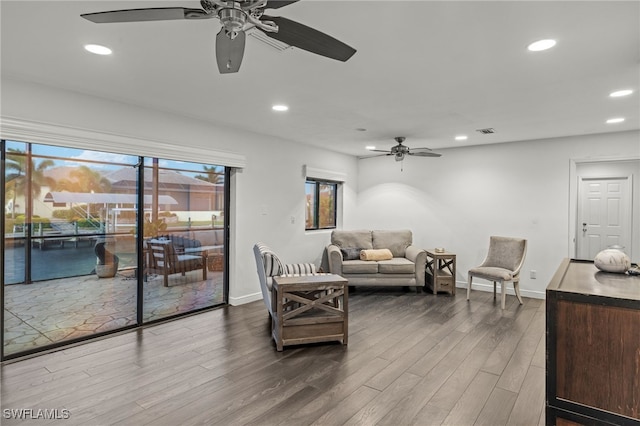 living area with a ceiling fan, recessed lighting, dark wood-type flooring, and baseboards