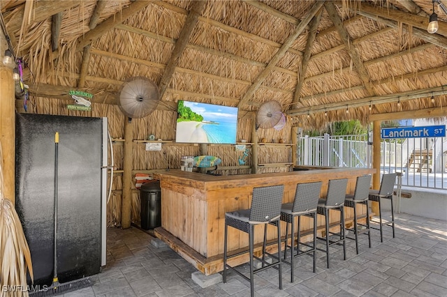 interior space with lofted ceiling with beams, stainless steel refrigerator, and wood walls