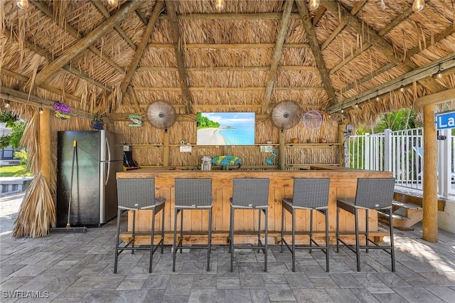 bar featuring lofted ceiling and stainless steel refrigerator