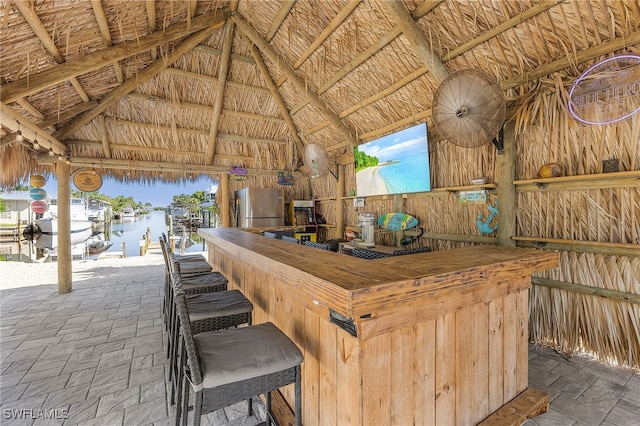 bar featuring high vaulted ceiling and stainless steel refrigerator