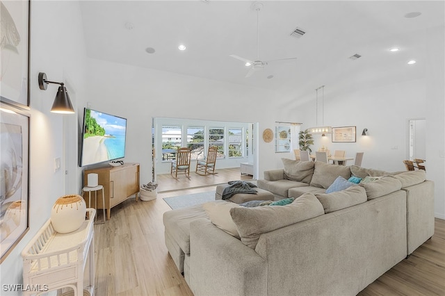 living room with ceiling fan, light hardwood / wood-style floors, and a high ceiling