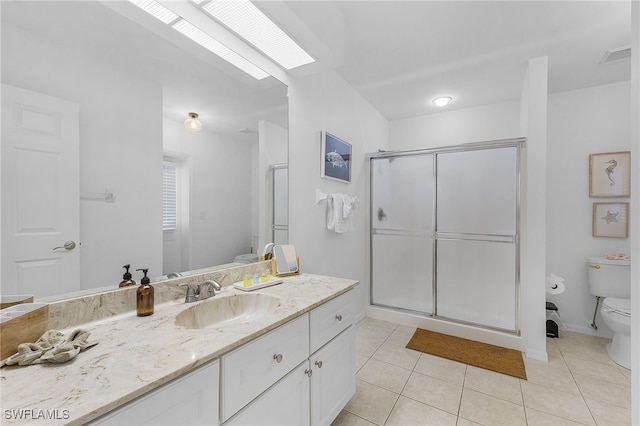 bathroom featuring tile patterned flooring, vanity, a skylight, and a shower with door