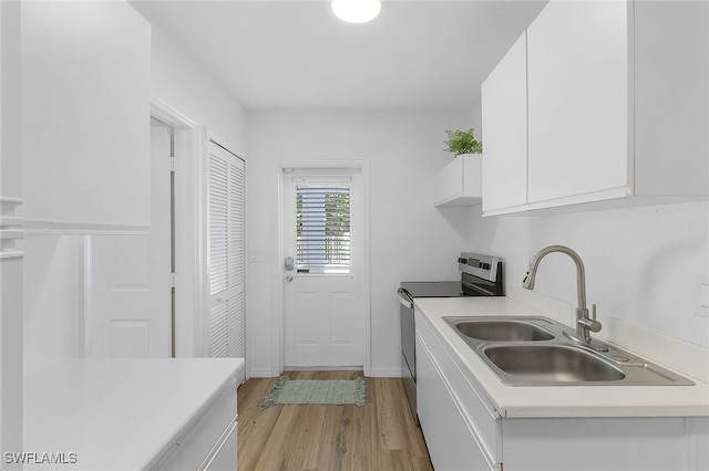 kitchen featuring sink, white cabinets, light hardwood / wood-style floors, and electric stove