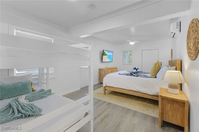 bedroom featuring beam ceiling, ceiling fan, a wall unit AC, and light hardwood / wood-style flooring