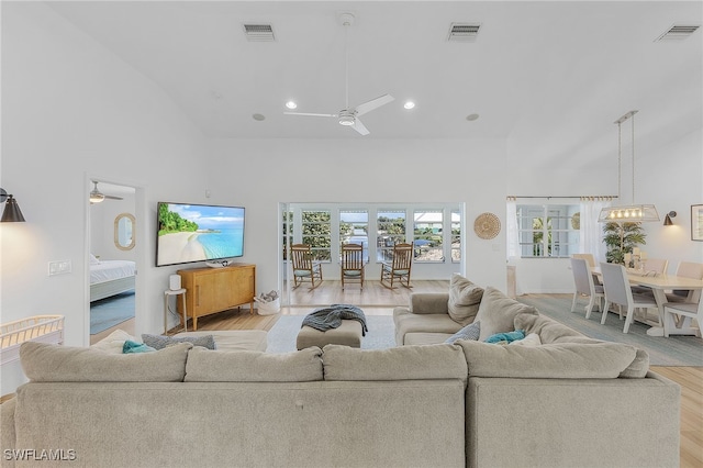 living room with ceiling fan, high vaulted ceiling, and light wood-type flooring