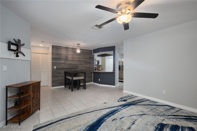 tiled living room featuring ceiling fan and wooden walls