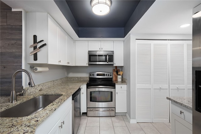 kitchen with white cabinetry, sink, light stone countertops, light tile patterned flooring, and appliances with stainless steel finishes