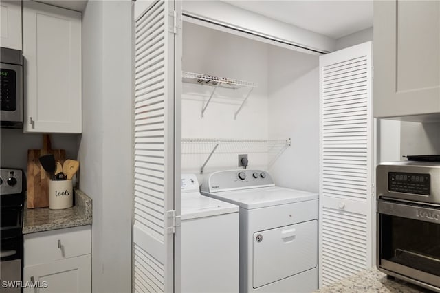 clothes washing area featuring washer and dryer and cabinets