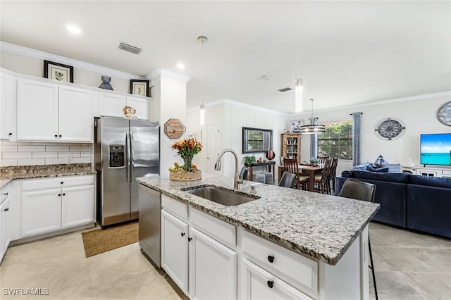 kitchen featuring sink, pendant lighting, a kitchen island with sink, white cabinets, and appliances with stainless steel finishes