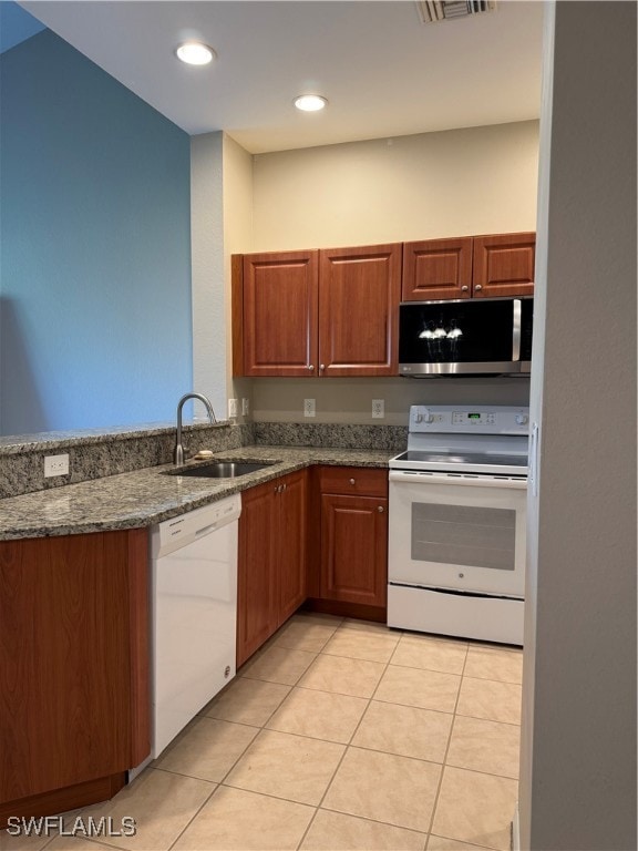 kitchen with sink, dark stone counters, white appliances, and light tile patterned floors