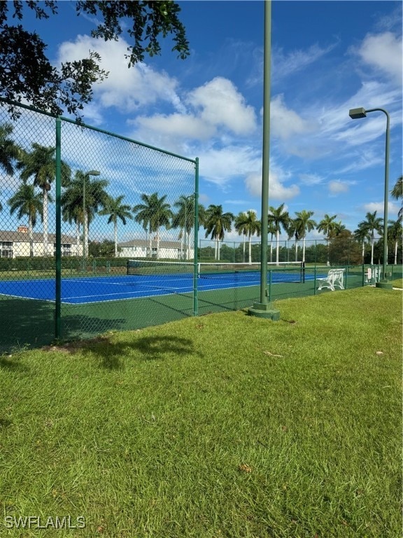 view of tennis court with a yard