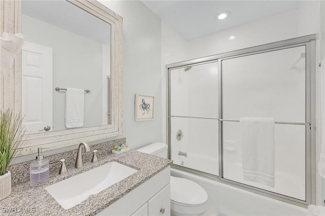 full bathroom with vanity, bath / shower combo with glass door, and toilet