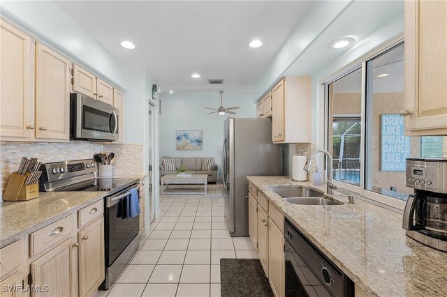 kitchen featuring light brown cabinets, light tile patterned floors, sink, appliances with stainless steel finishes, and light stone countertops