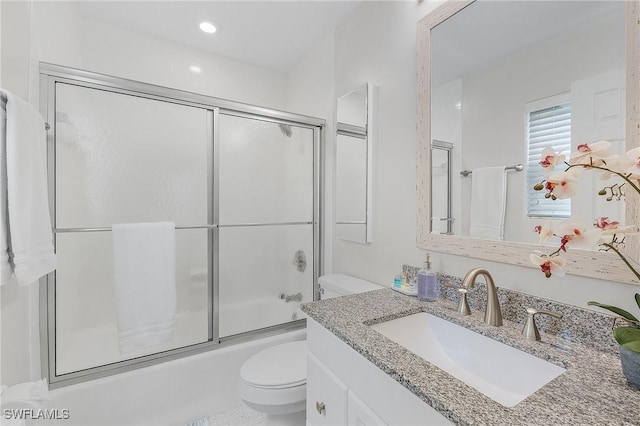 full bathroom with combined bath / shower with glass door, vanity, and toilet