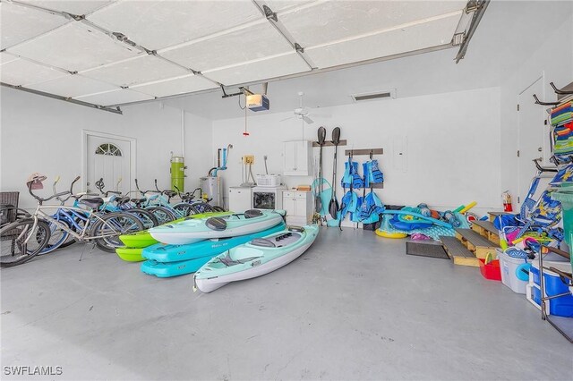 garage with gas water heater, a garage door opener, ceiling fan, and independent washer and dryer