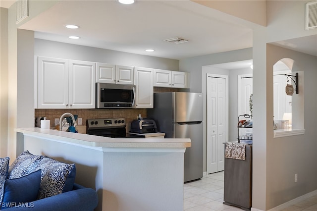 kitchen featuring appliances with stainless steel finishes, kitchen peninsula, decorative backsplash, and white cabinetry