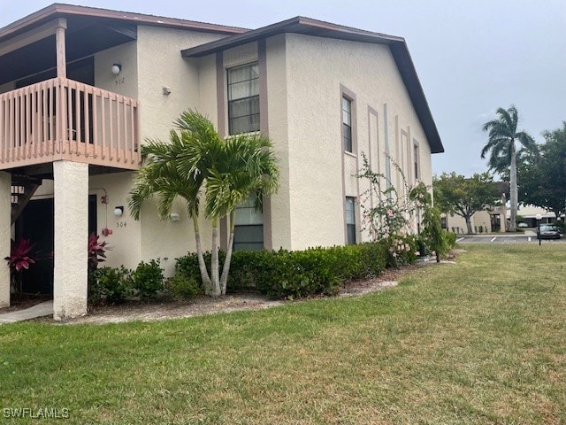 view of side of home featuring a balcony and a yard