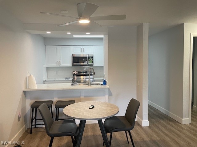 kitchen with dark wood-type flooring, sink, white cabinets, stainless steel appliances, and ceiling fan