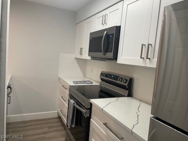 kitchen featuring appliances with stainless steel finishes, decorative backsplash, white cabinets, light stone countertops, and dark hardwood / wood-style floors