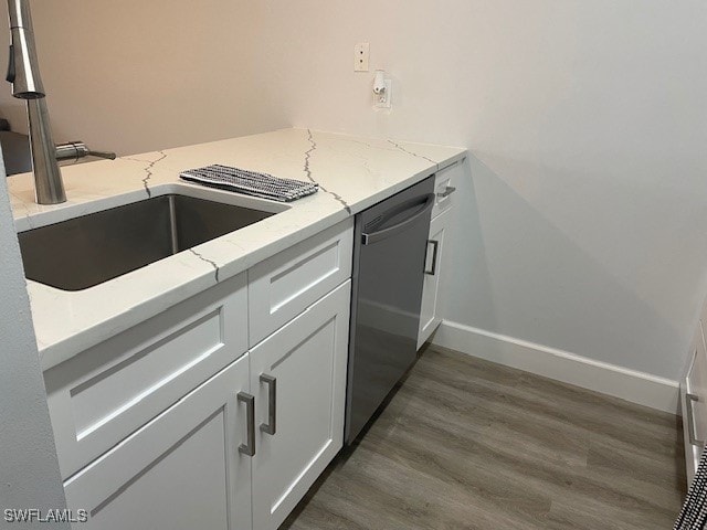 kitchen with dishwasher, sink, white cabinets, dark hardwood / wood-style flooring, and light stone countertops