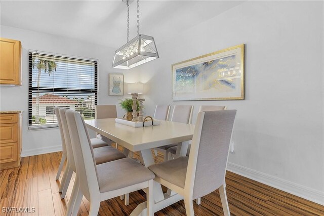 dining area with wood-type flooring and a chandelier