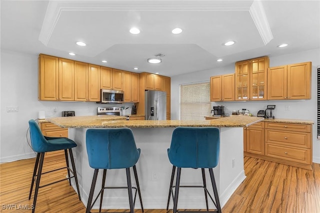 kitchen featuring light stone counters, a breakfast bar area, a center island, and appliances with stainless steel finishes