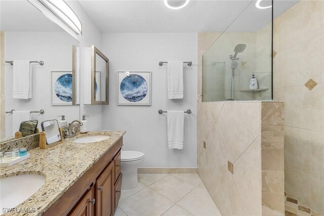 bathroom featuring tile patterned flooring, toilet, vanity, and tiled shower