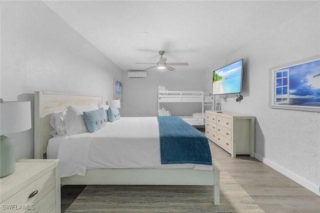 bedroom featuring an AC wall unit, ceiling fan, and light wood-type flooring