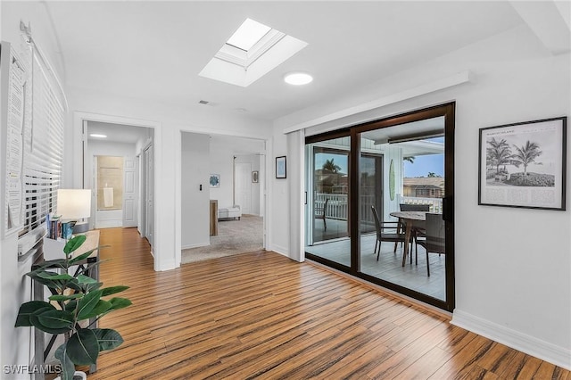 hall featuring hardwood / wood-style flooring and a skylight