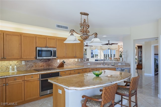 kitchen featuring a center island, a kitchen breakfast bar, stainless steel appliances, decorative light fixtures, and light tile patterned floors