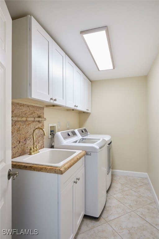 washroom with sink, light tile patterned floors, cabinets, and washer and clothes dryer