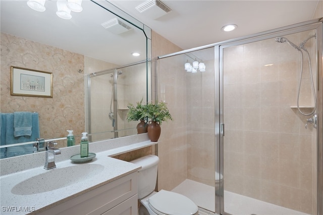 bathroom featuring a shower with door, vanity, and toilet