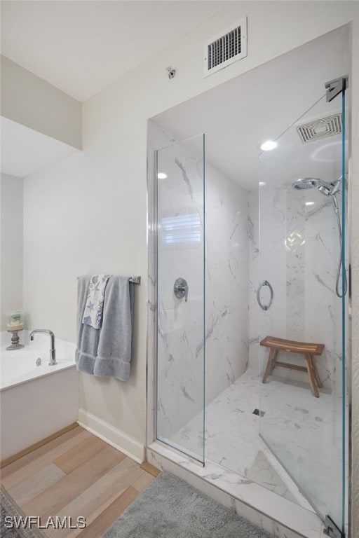 bathroom with independent shower and bath and hardwood / wood-style floors