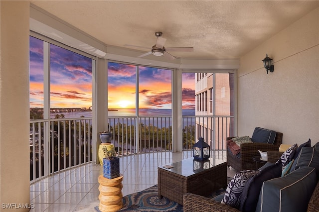 sunroom / solarium featuring a water view and ceiling fan